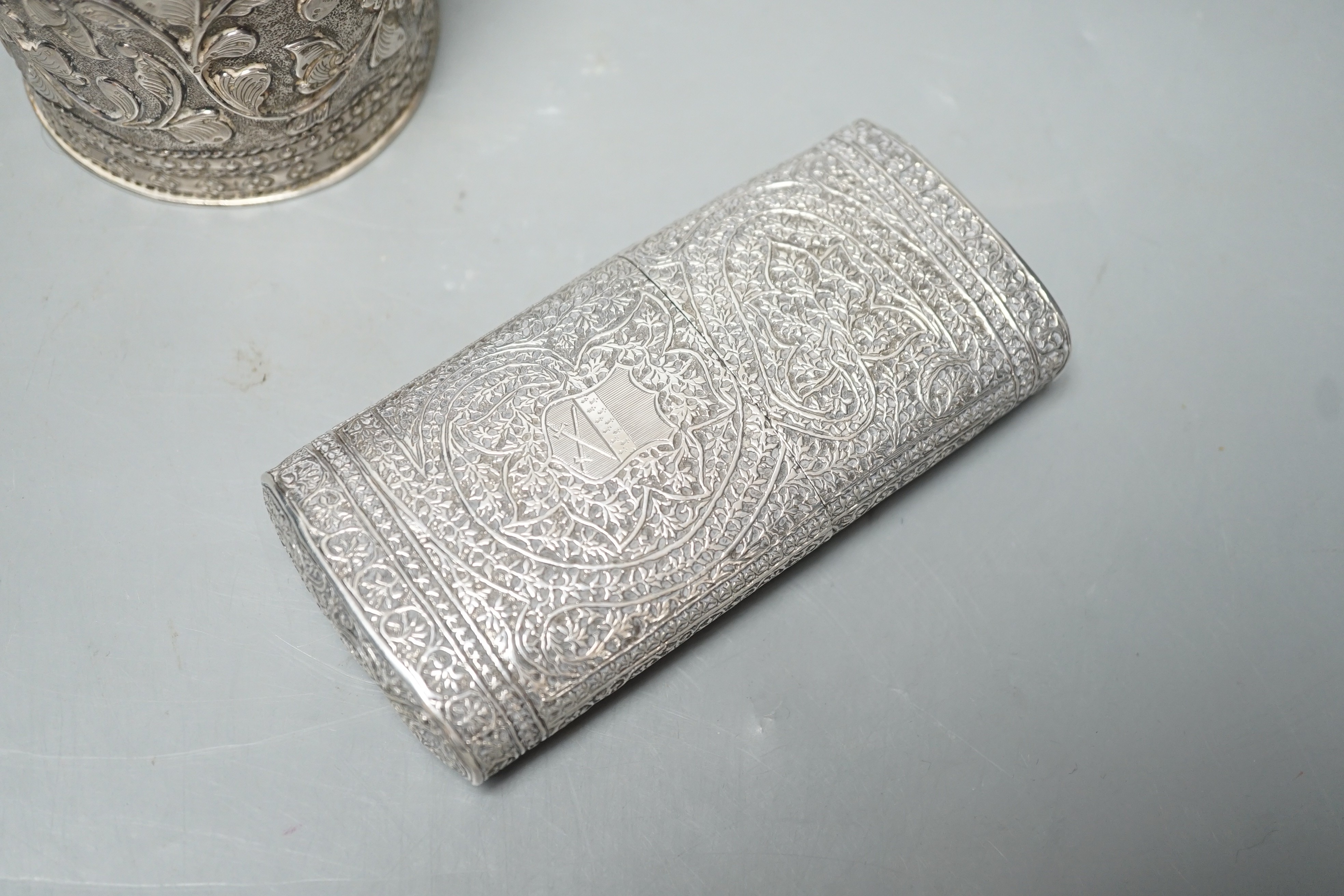 An Indian embossed white metal cigar case, 12.2cm and a similar canister and cover.